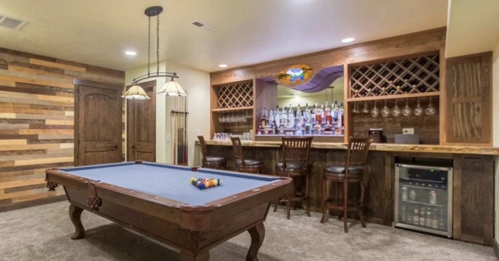 Custom barnwood basement bar with diamond wine lattice storage, a live-edge counter and a reclaimed wood accent wall