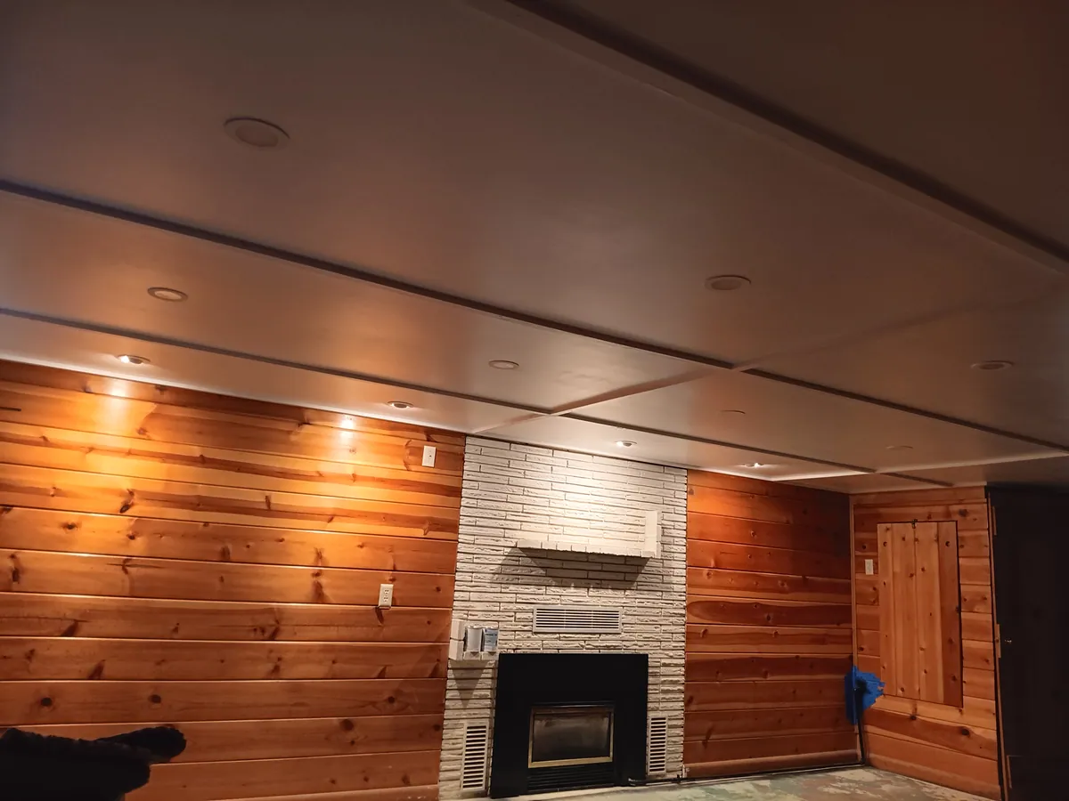 Finished basement ceiling with recessed can lights and bare concrete floor