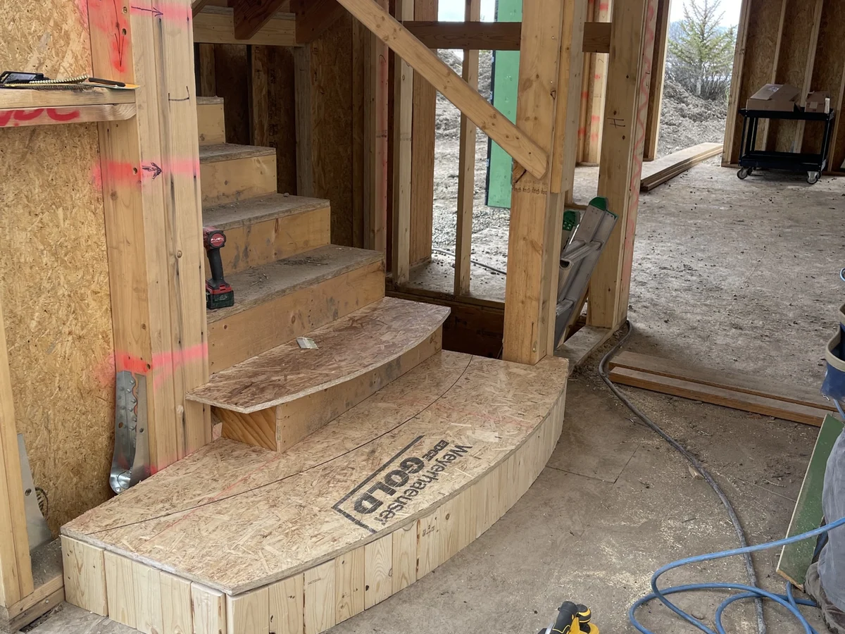 Rough stair framing with a curved bottom tread and landing built on site