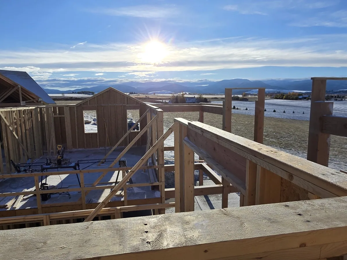 Deck framing we built — joists, rim and railing posts set, photographed at sunrise over the Missoula valley