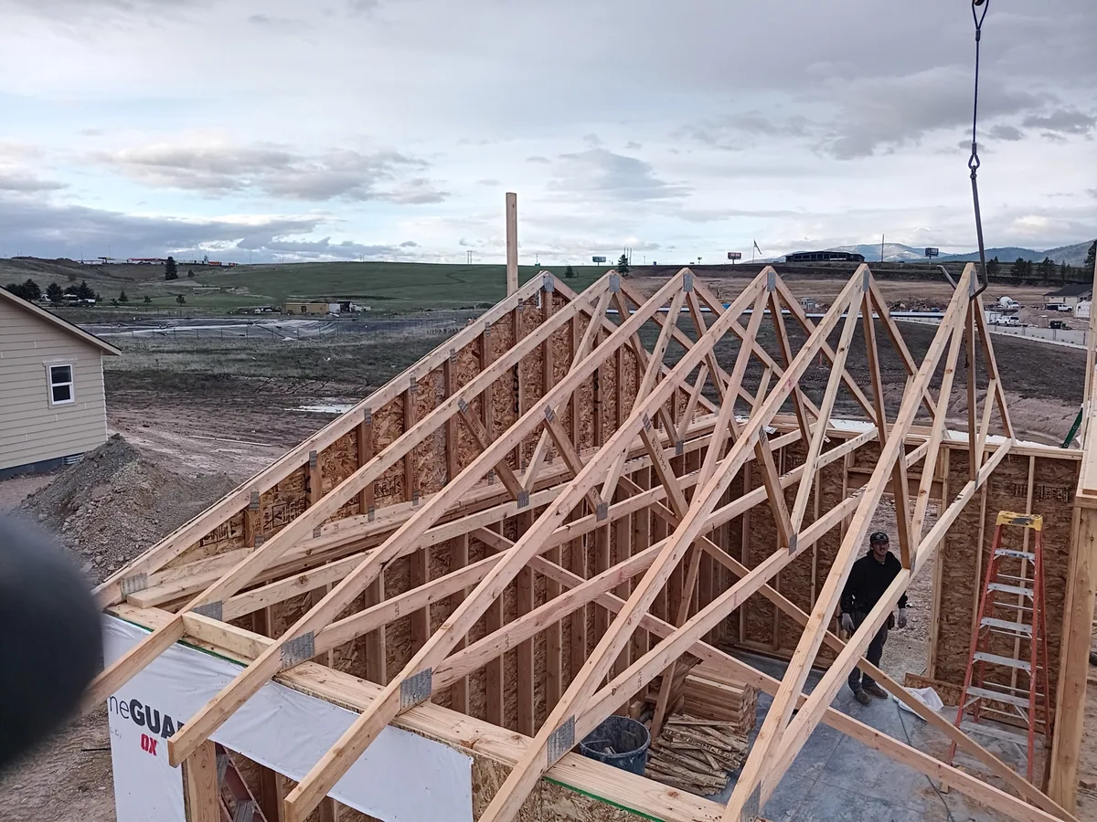 Roof trusses standing on a framed house in a new subdivision under an overcast sky