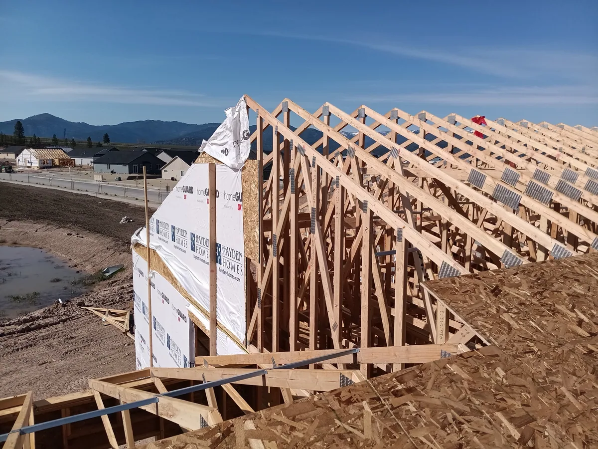 A long run of roof trusses set and braced on a new home with mountains behind