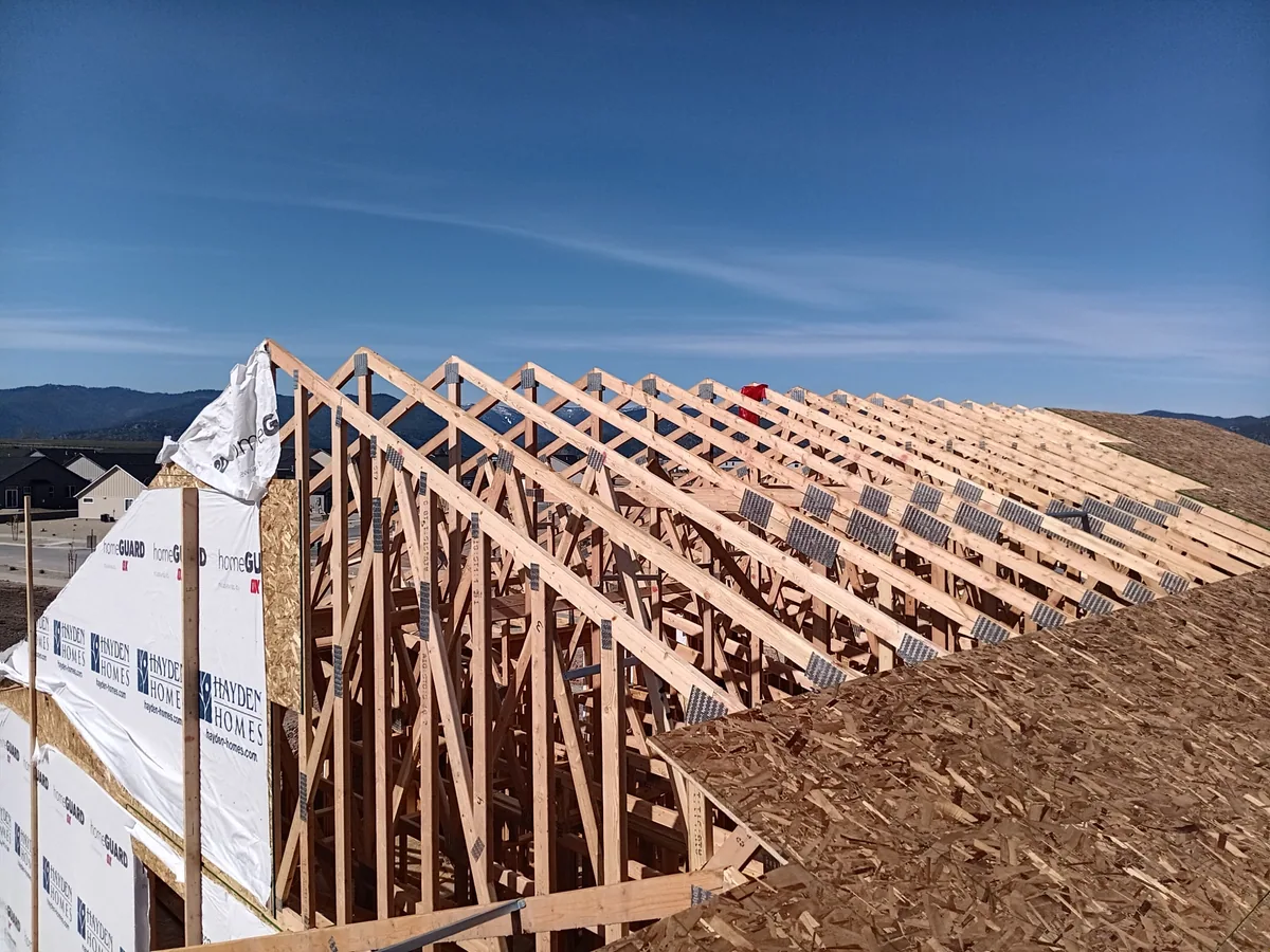 A long row of roof trusses set and braced across a new home in a subdivision