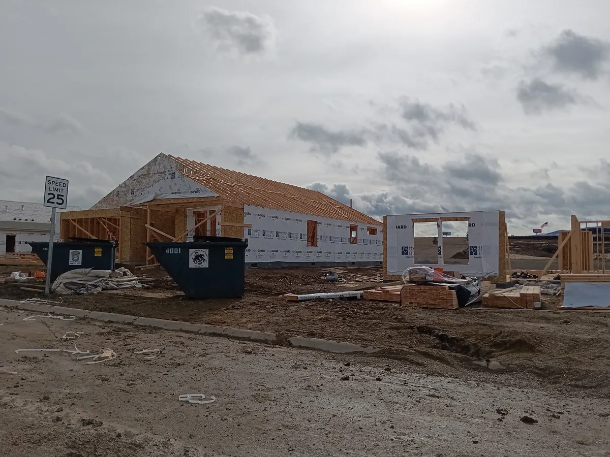 A large building framed and standing on a muddy winter job site