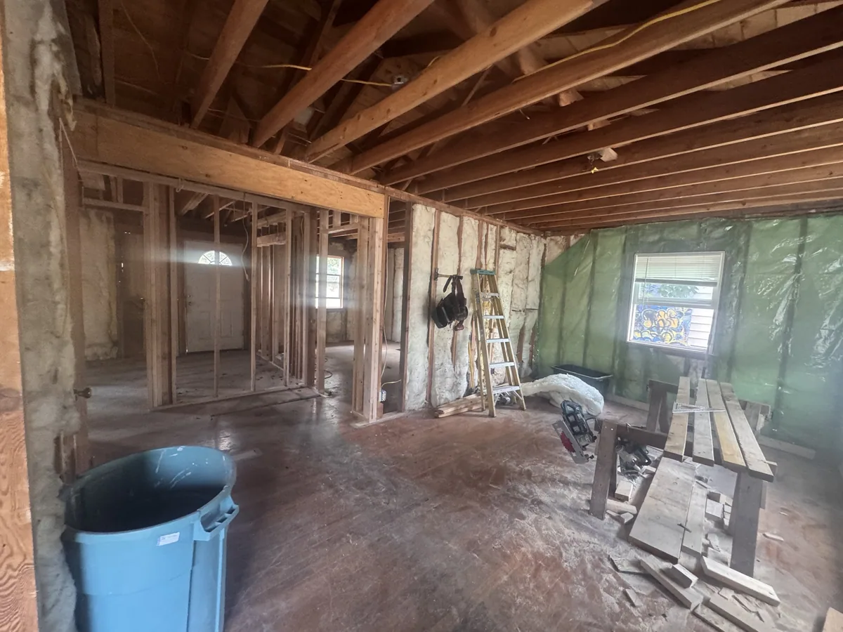 Framed interior of a gut remodel with exposed joists overhead and new stud walls