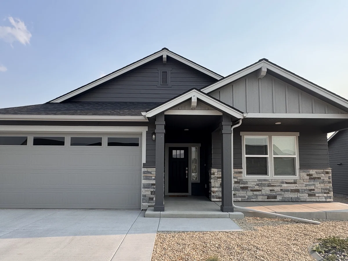 A home we sided in dark lap siding and board-and-batten with new trim, fascia and stone veneer