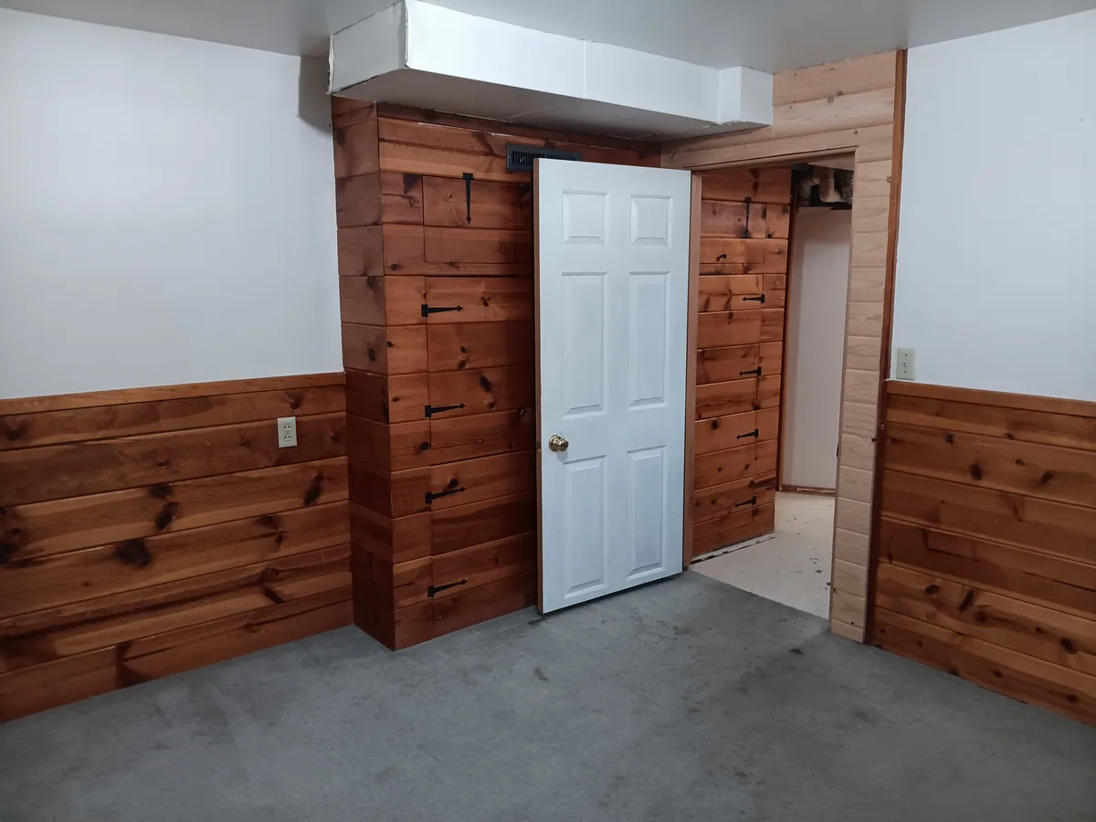 Cedar wainscot and a new white six-panel door installed in a finished basement